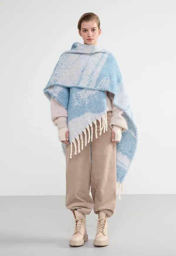 Stickad poncho med fransar